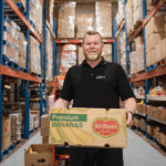 Food 4 All staff member holding a box in the warehouse.