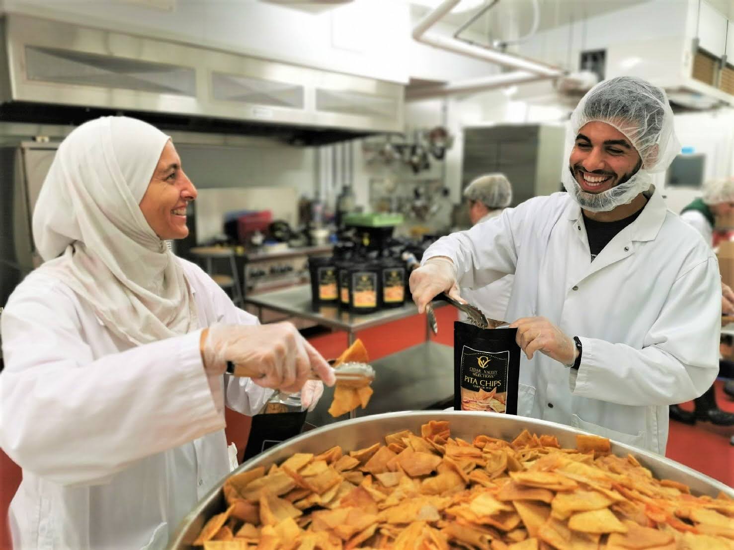 Business owners pack chips into a bag in OAFVC commercial kitchen