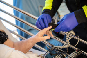 Close up of Community Paramedic measuring patient's vital signs with a fingertip oximeter