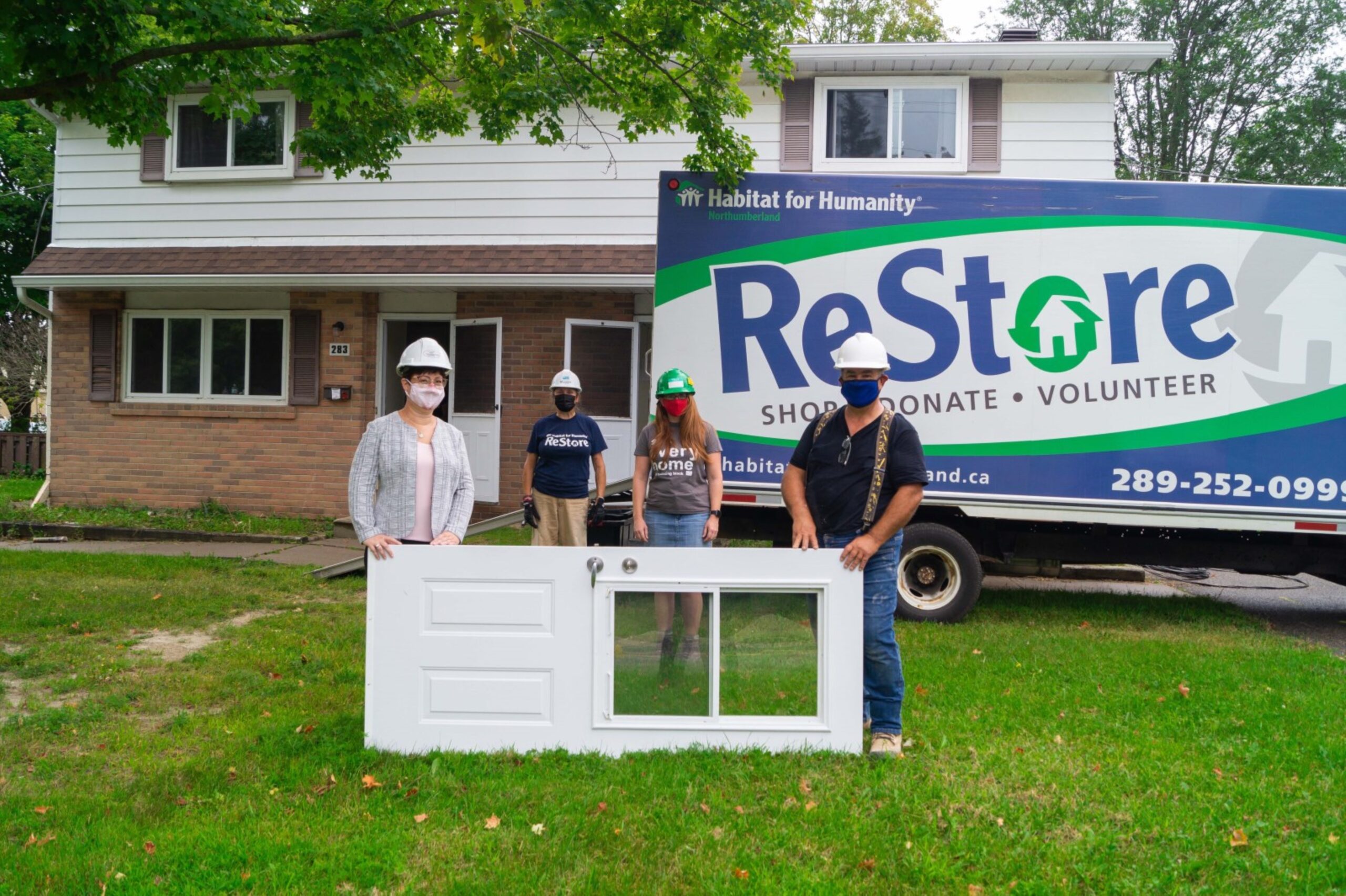ounty staff standing outside of a home at Elgin park with a Habitat for Humanity van parked in the driveway.