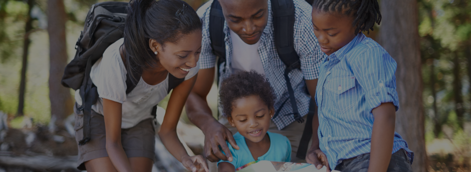 Family gathers around a map while exploring outside