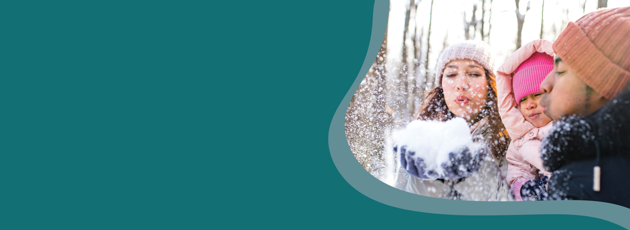 Family of three blow snow from their hands into the air