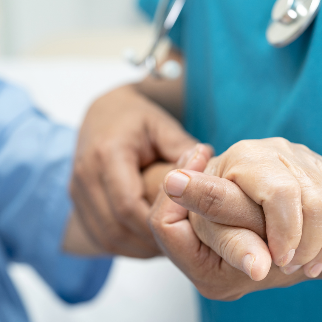 Nurse holding the hand of an older patient.