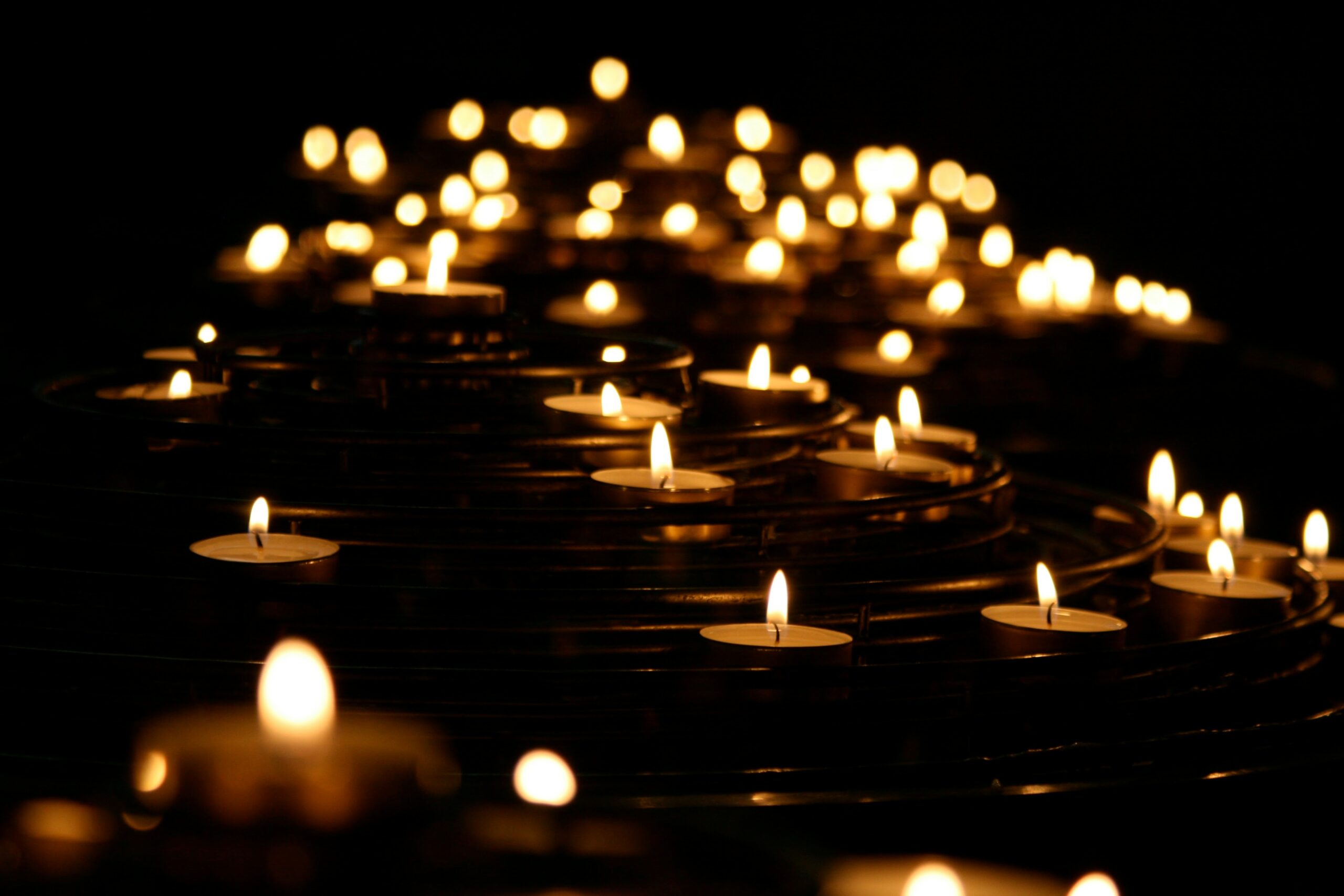Various candles burning in a dark area.