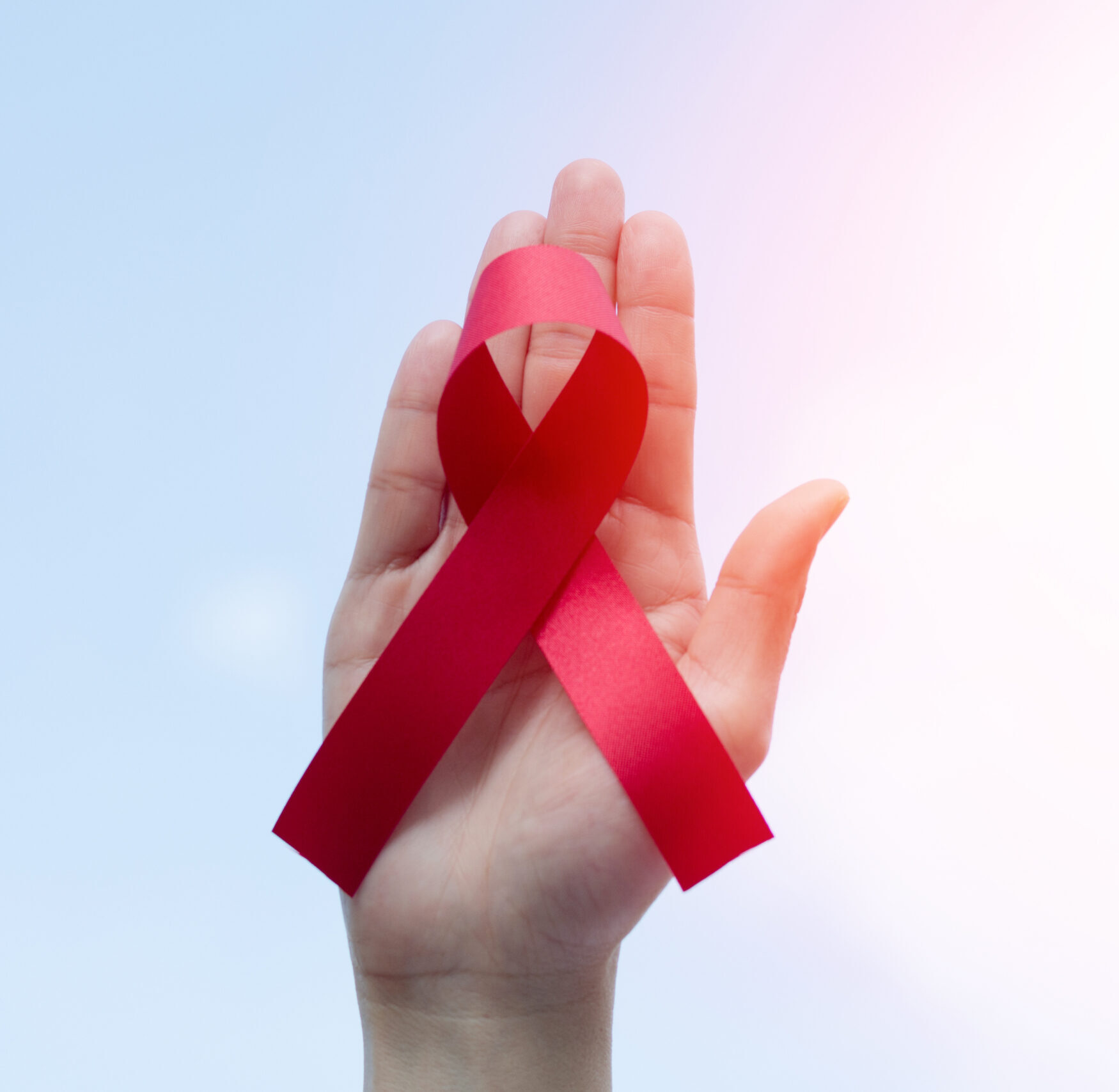 Red awareness ribbon on a hand.