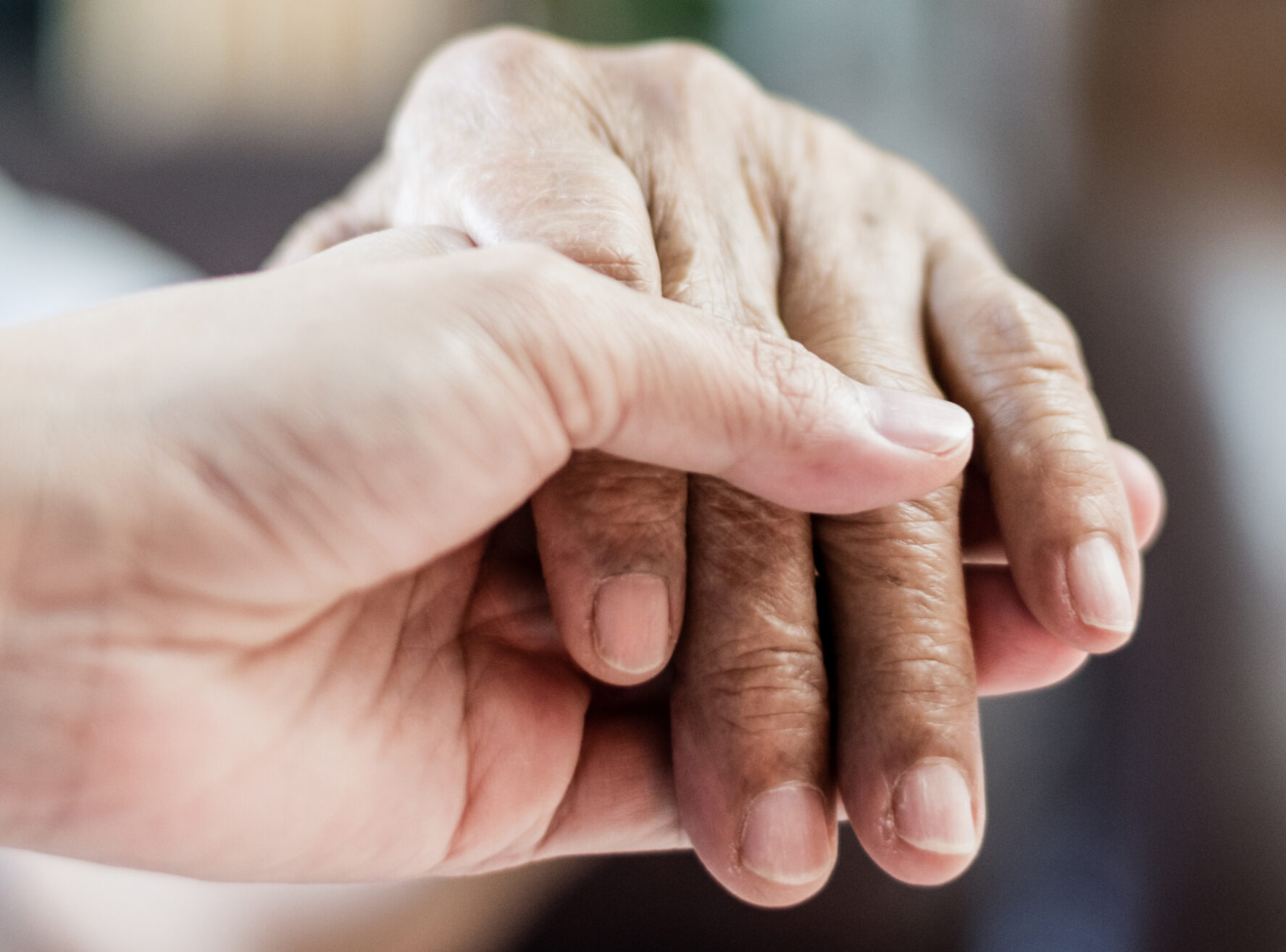 hand holding the hand of an older adult.
