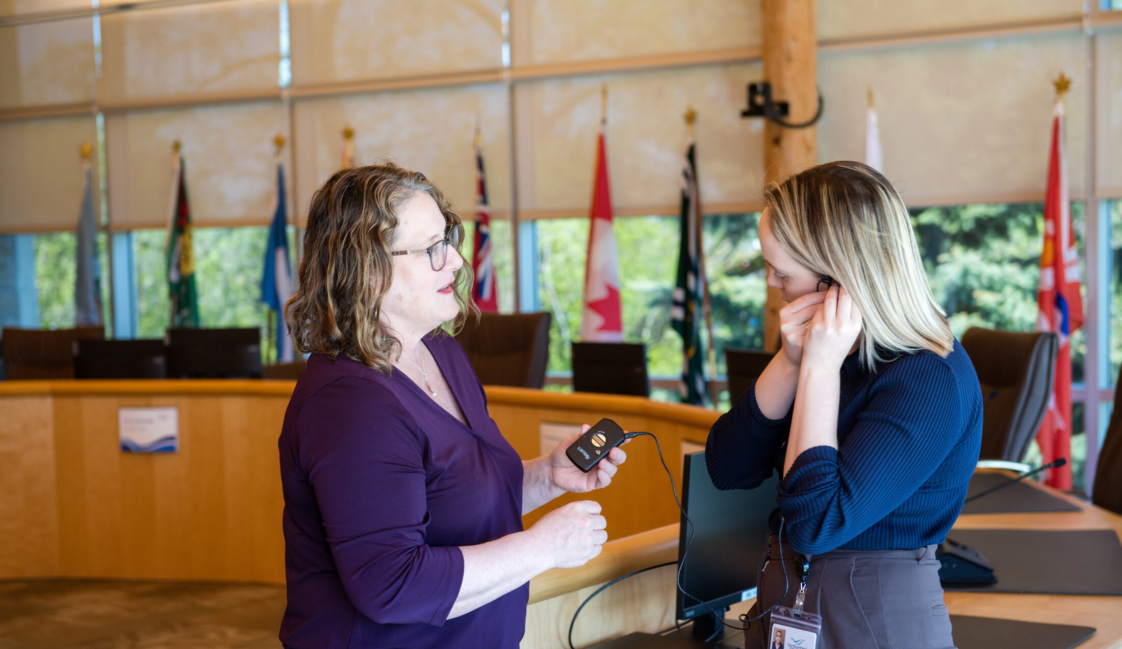 County staff member supporting a community member with using the assistive listening device in County Council chambers.