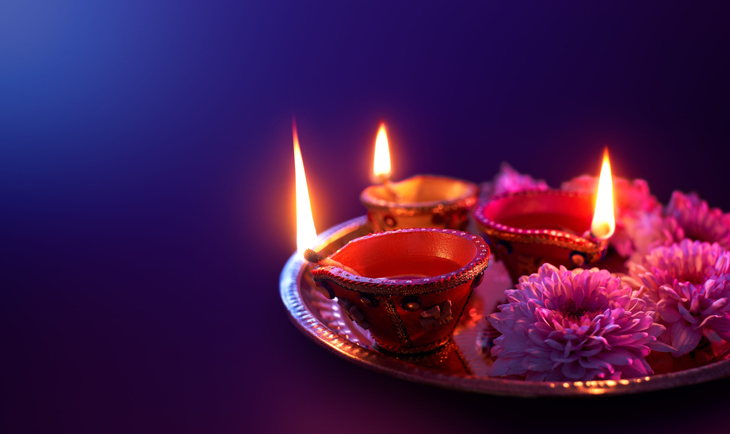 Traditional Diwali items with candles burning on a plate.