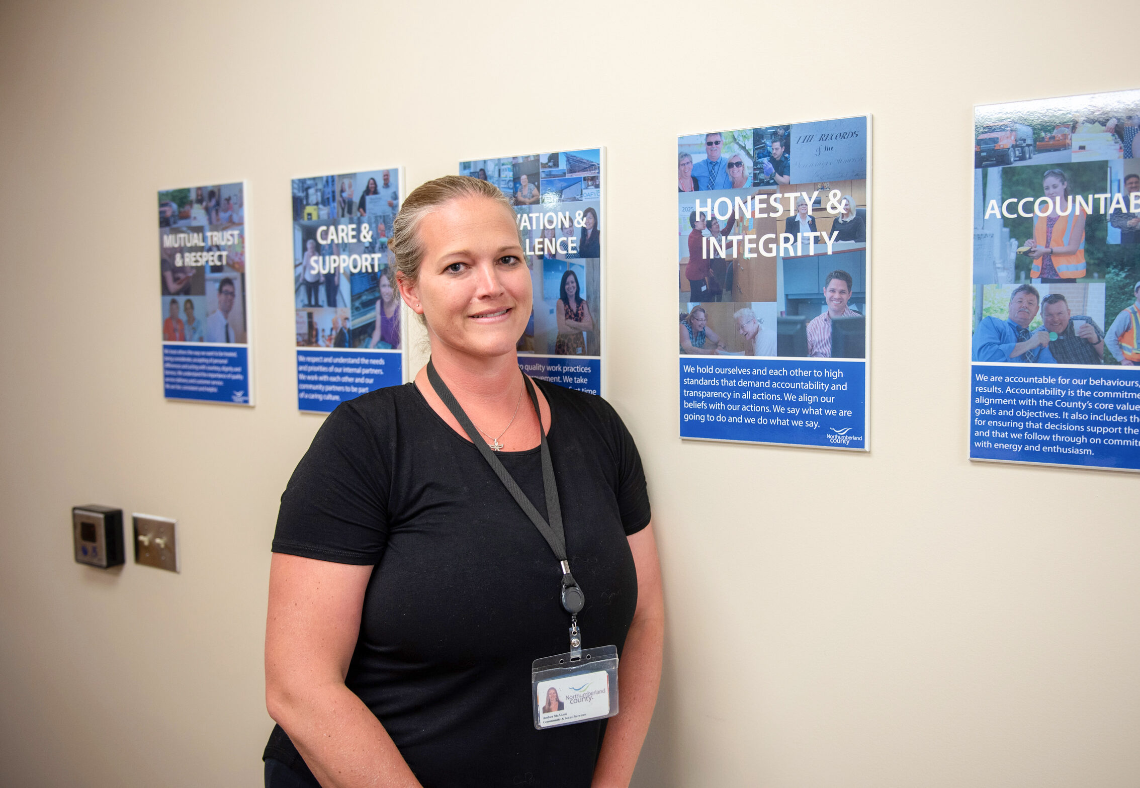 Staff member poses next to posters of organization’s core values