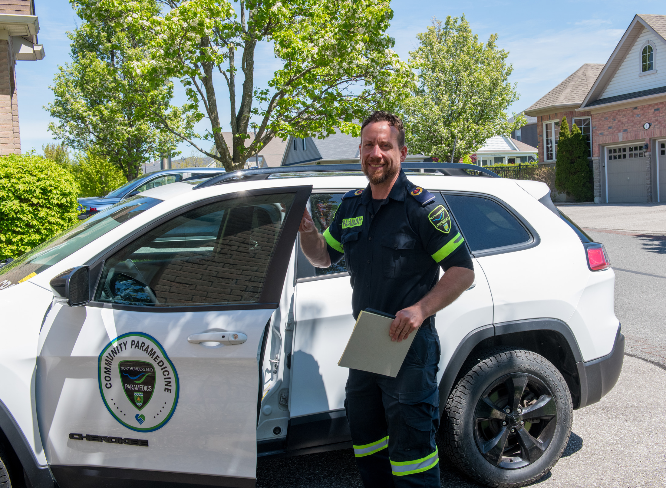 Community Paramedic smiles at camera as he opens door to vehicle