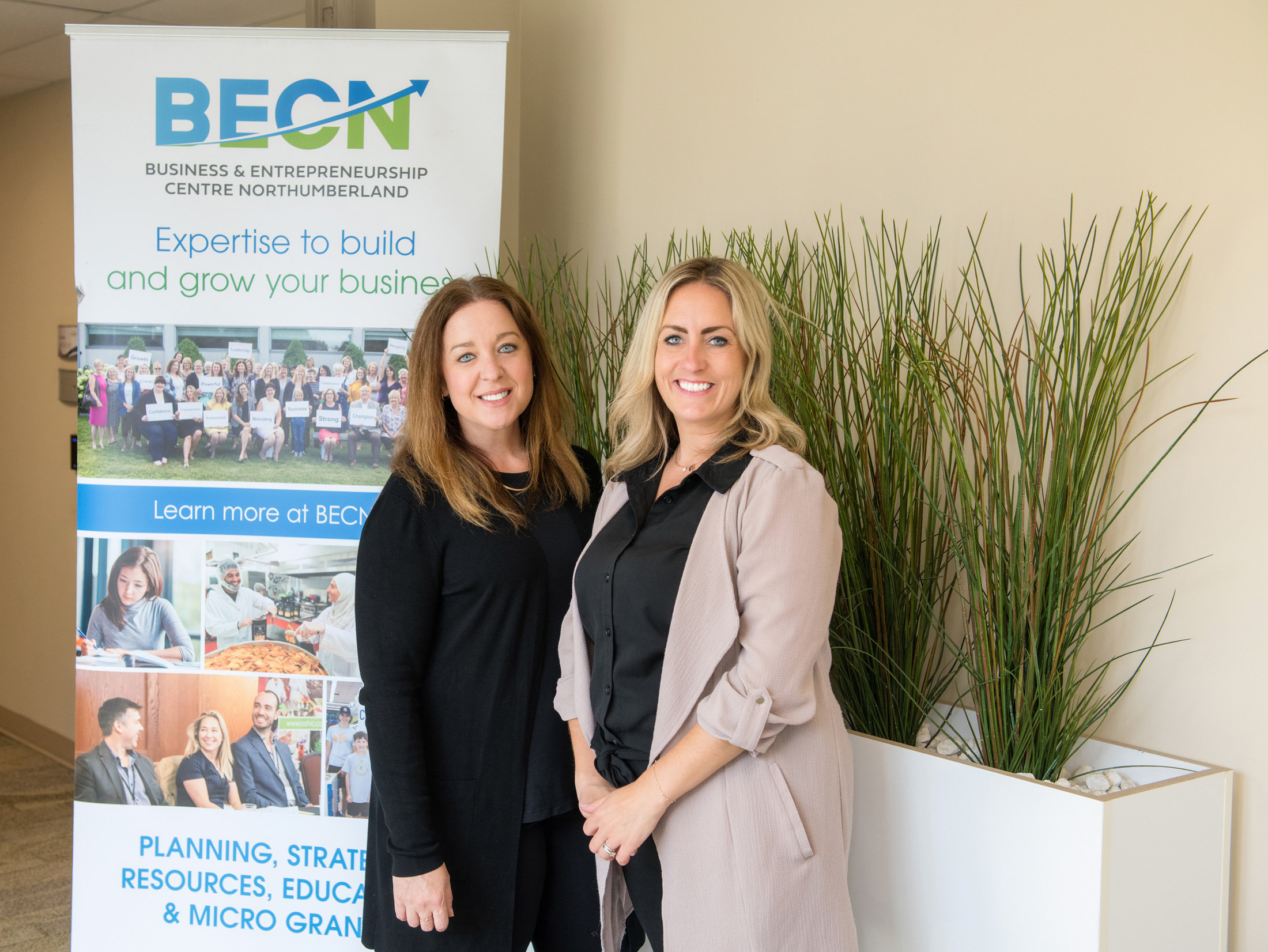 BECN staff smile next to promotional banner