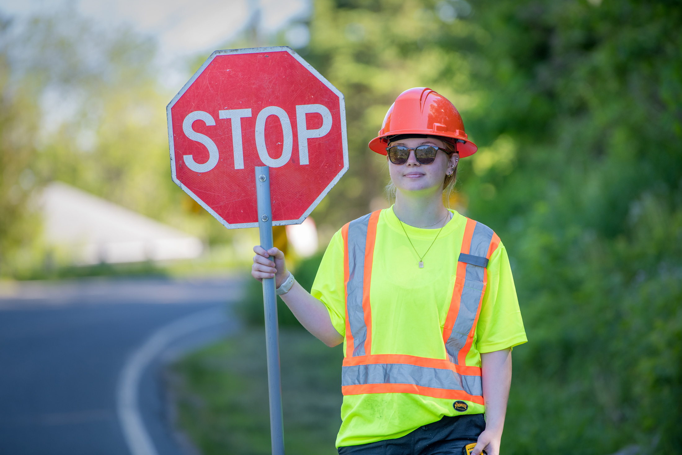 Roads student holds up a stop sign at construction site