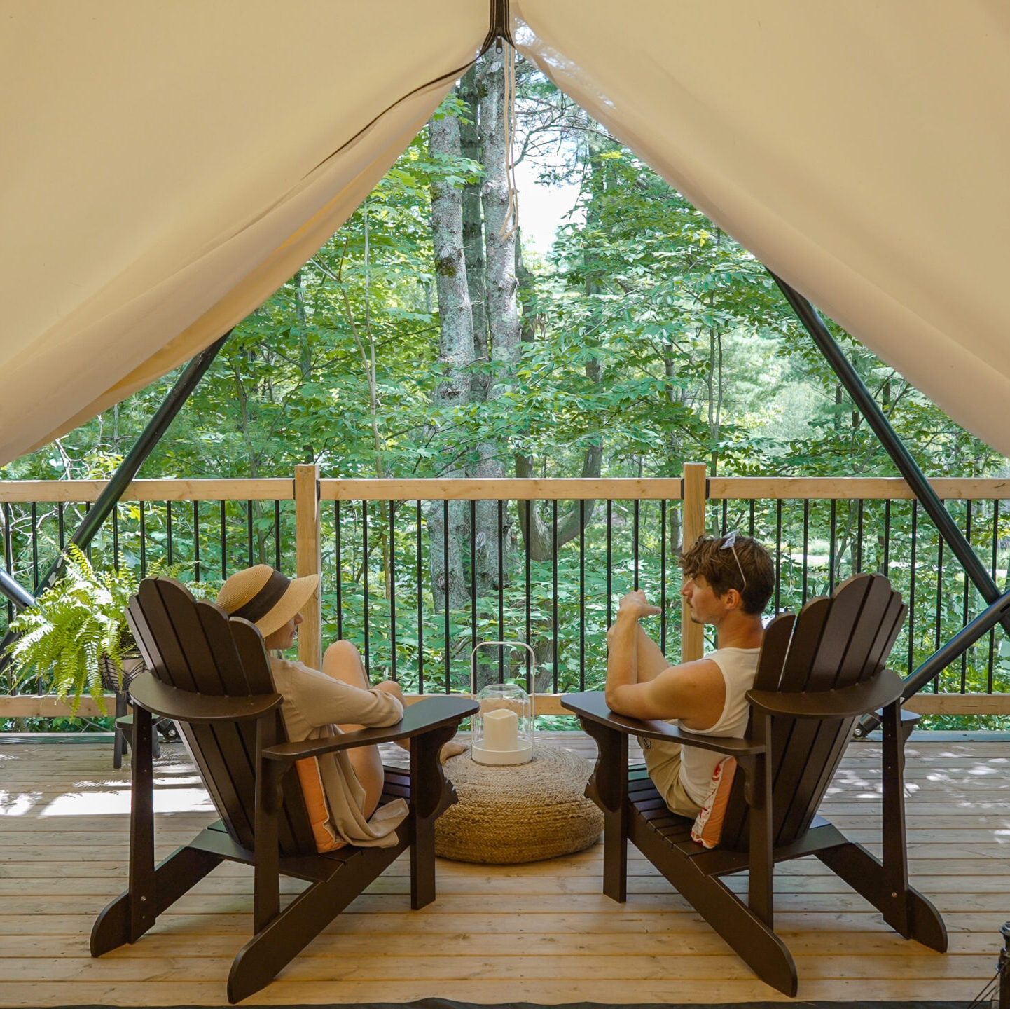 Two tourists sit in Muskoka chairs in a tent at Whispering Springs