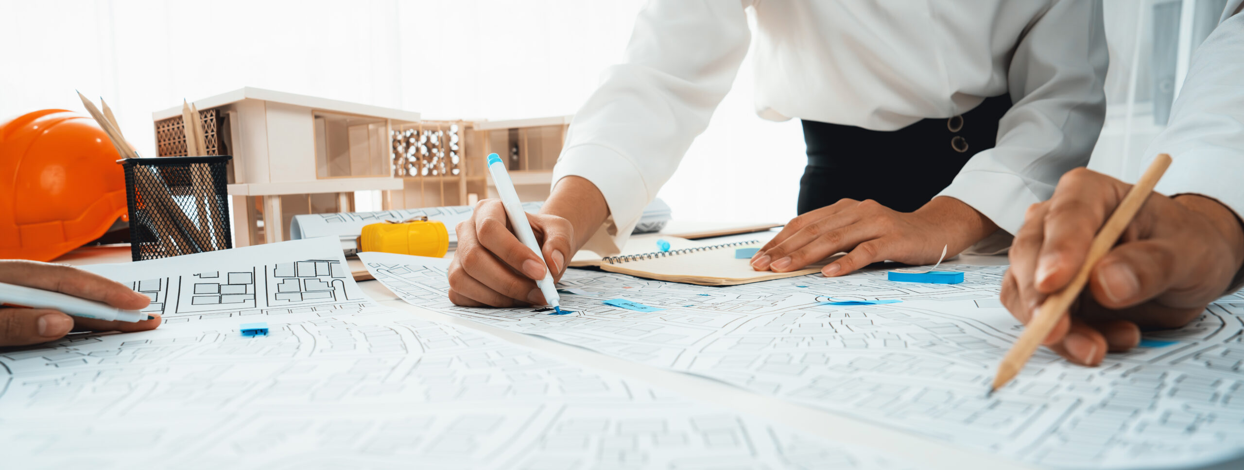 Staff working on a blueprint spread out over a table.