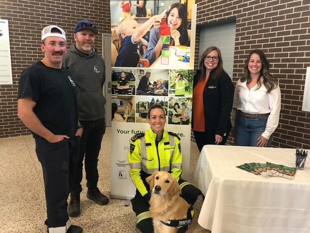 County staff pose next to booth at high school visit