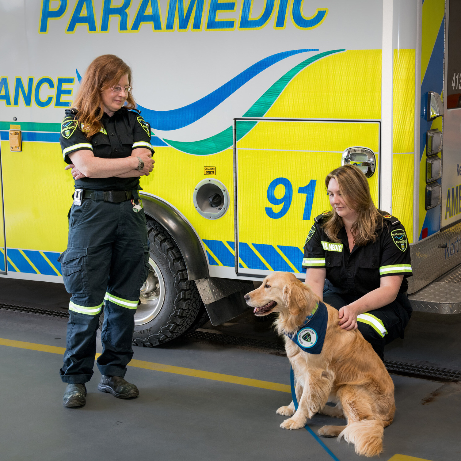 Two Northumberland paramedics standing in front of an ambulance with Ivy Jules the paramedic's therapy dog.