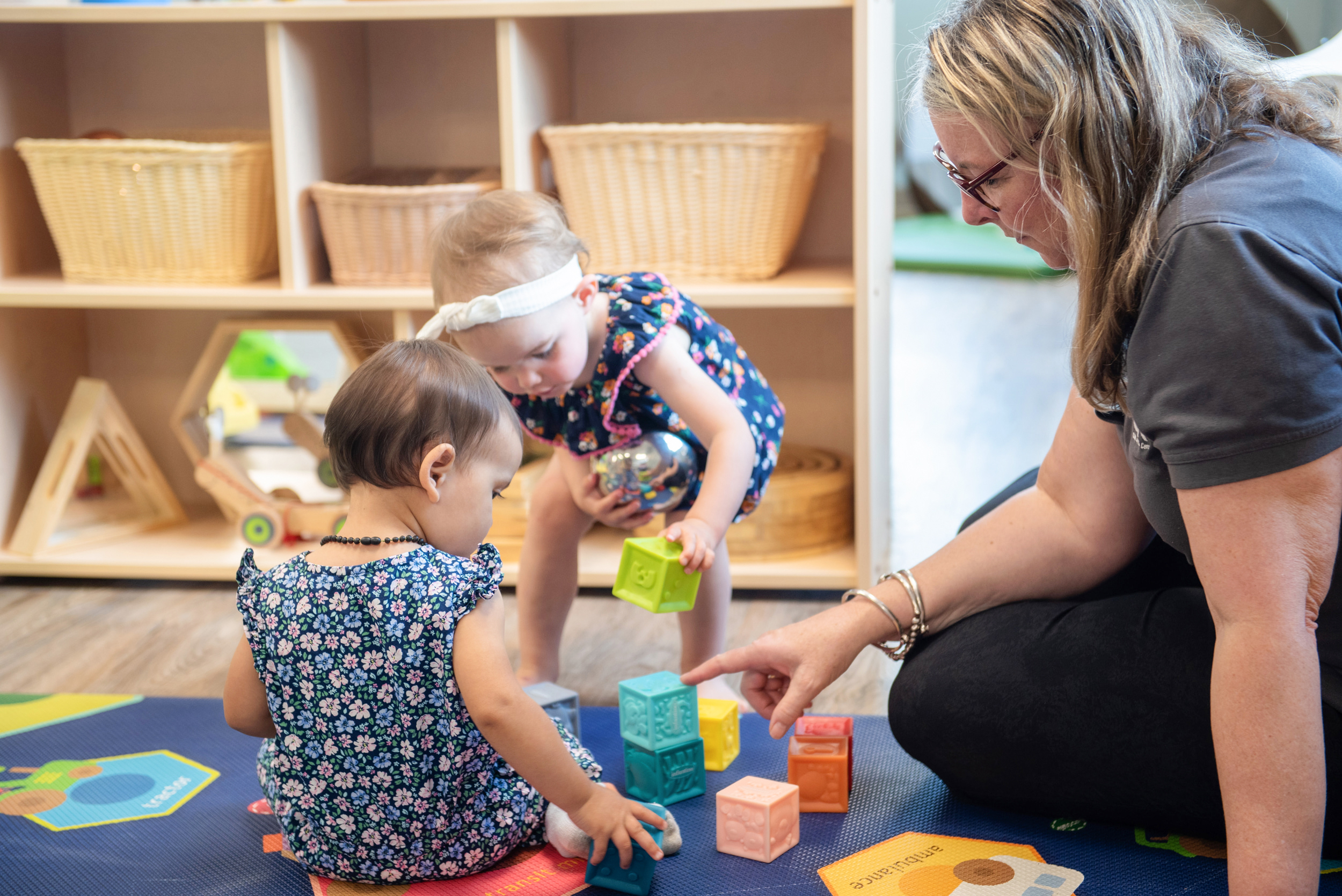Child care worker interacting with children with building blocks.